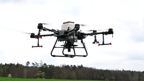 Modern-Agriculture-Drone-Sprayer-Hovering-Above-Green-Farming-Field,-Close-Up-50fps