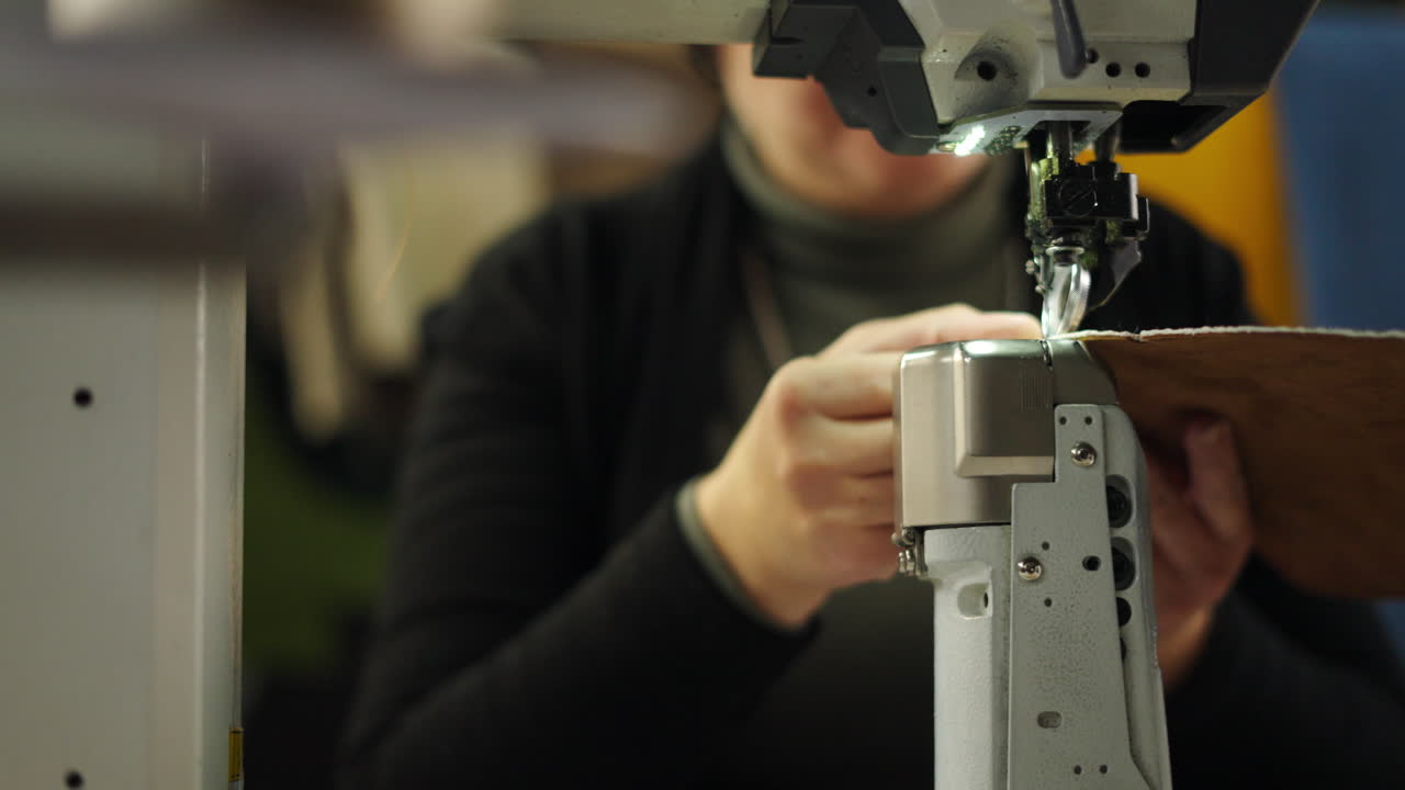 Woman operating a sewing machine working with leather