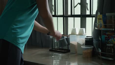wide static shot of apartment resident organizing items on cozy kitchen table by the window during daytime.