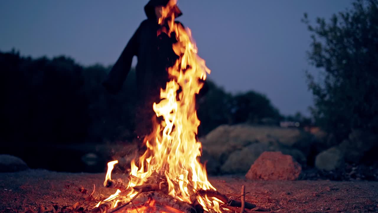The old witch cooks a sorcery potion in the thicket of the forest. Fairy tales on Halloween. Burning fire.