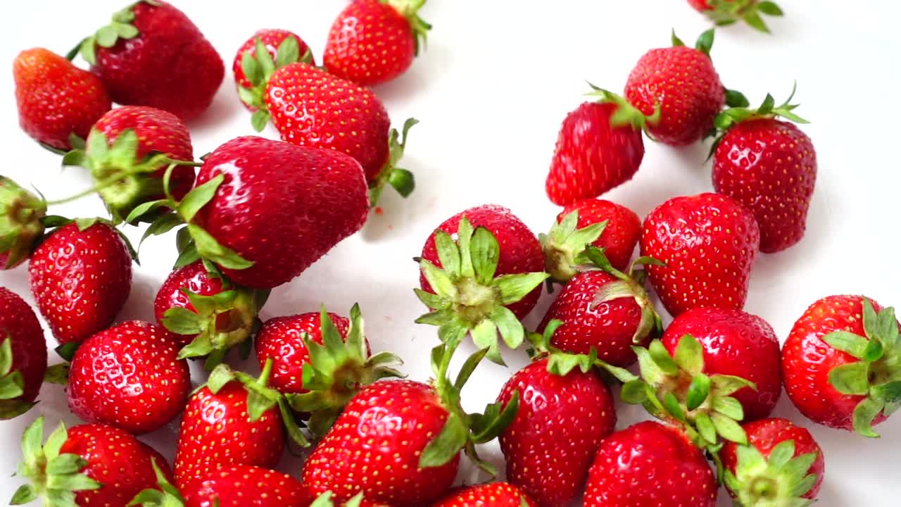 Herunterfallende Erdbeeren auf weißem Hintergrund. Zeitlupe. Erdbeeraufnahme.