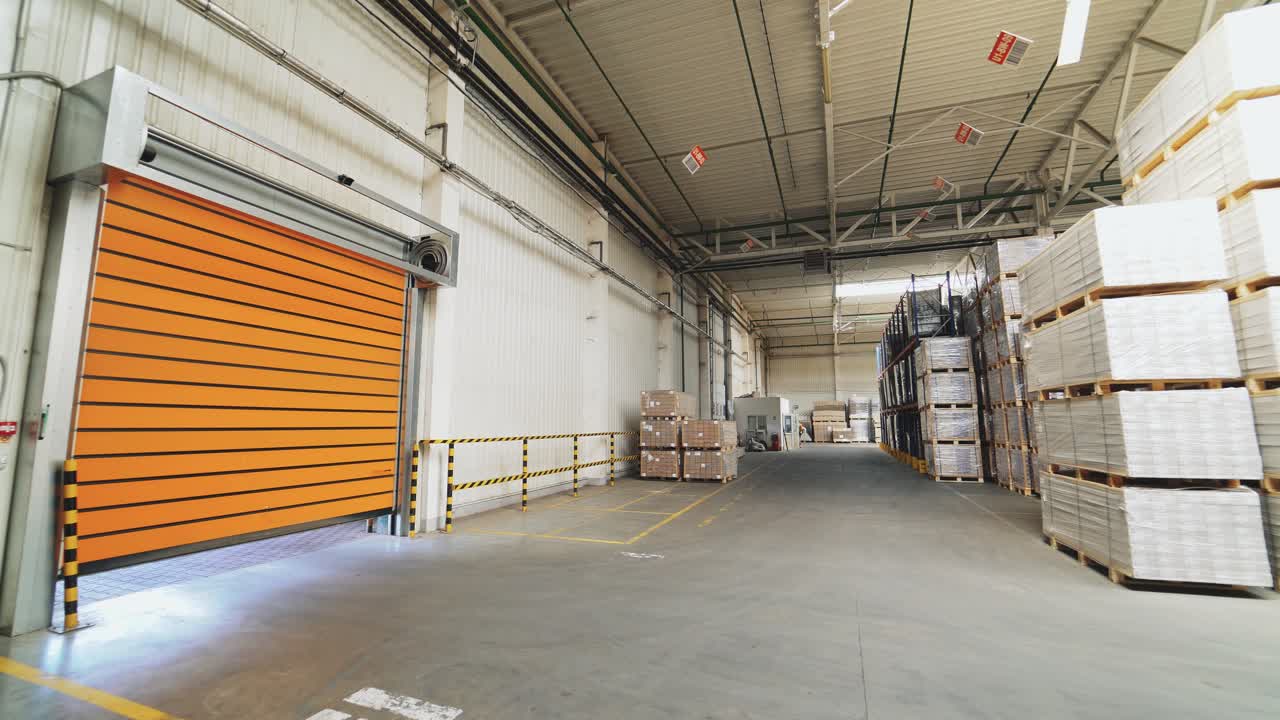 Orange rolling door of the warehouse is closing. Rolettes work with the help of automation. Motion of rolling door to down