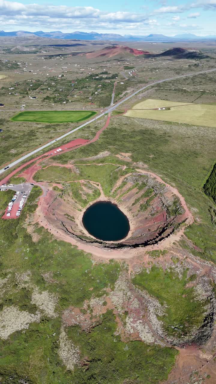 Extreme wide drone view around the Kerid crater volcanic lake in Iceland, vertical video.