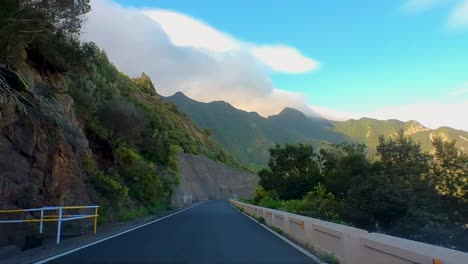 cinematic drive on a curvy empty mountain road, surrounded by tall green mountains, clear blue sky, canary islands, tenerife, spain