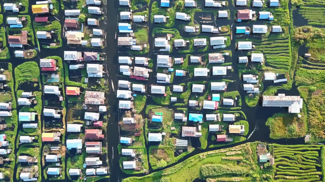 Inle lake's unique ecosystem supports floating gardens and stilt houses, creating a captivating scene of human adaptation to the watery environment, overhead aerial shot zooming in