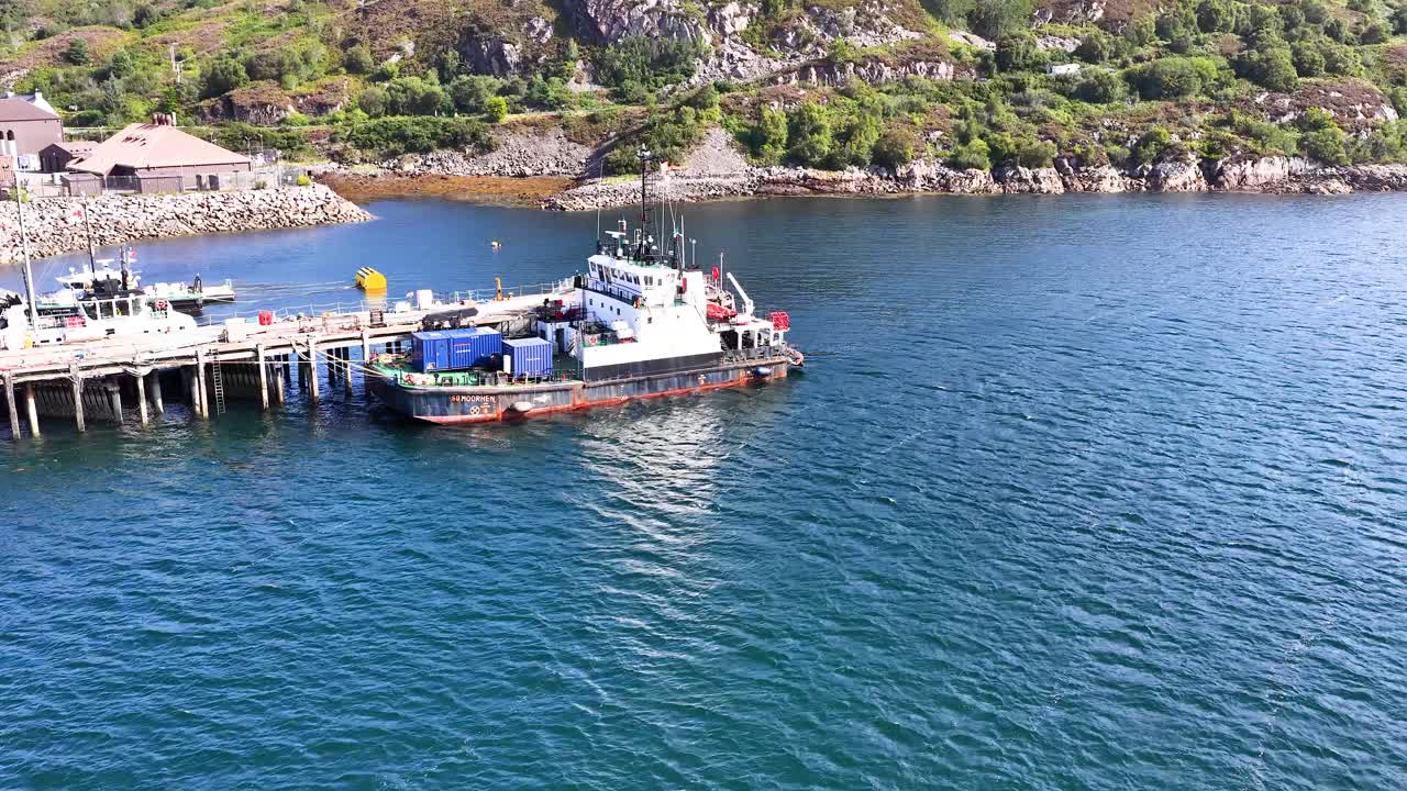 Fishing vessel approaches pier in Dundee harbor, Scotland, under bright daylight with smooth aerial movement