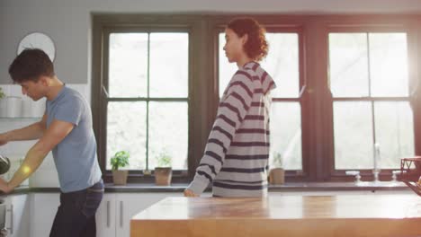 happy diverse male couple drinking coffee and embracing in kitchen