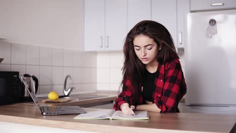 una joven atractiva escribiendo algo en su computadora portátil. se siente cansada y finalmente pone su cabeza sobre la mesa.