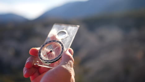 close up on a hand holding a scratched magnetic compass with the epic forest and mountains of california in the background