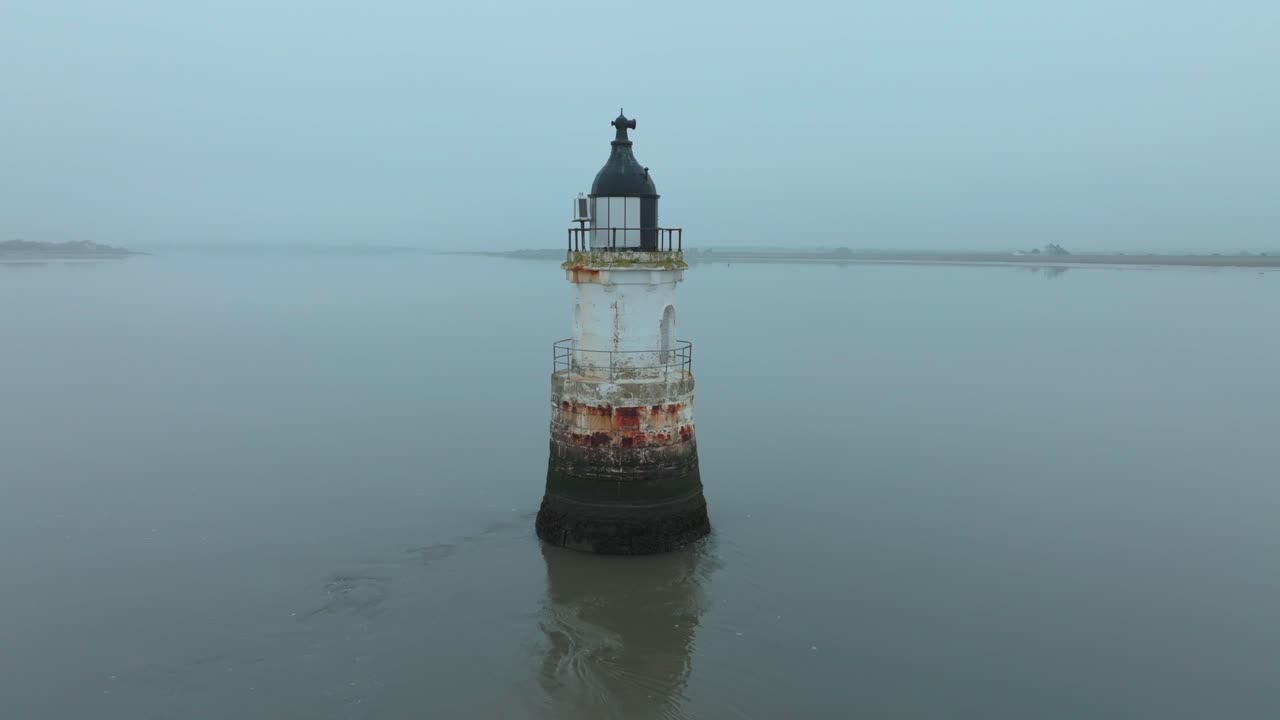Slow Approach to Derelict Rusted Lighthouse In Calm Tidal Water With Misty Coastline Behind. Plover Scar Lighthouse, Lancashire, UK