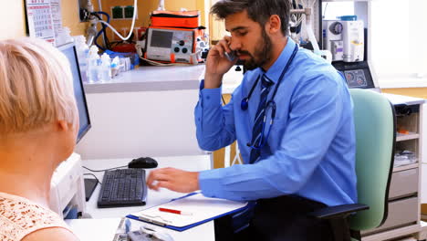 médico sentado en su escritorio y hablando por teléfono