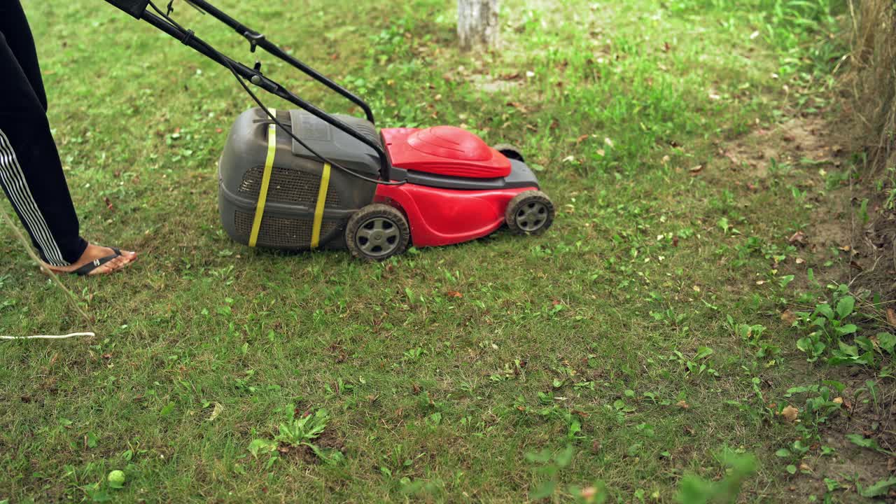 Garden works and equipment. Worker using lawn mower for cutting grass