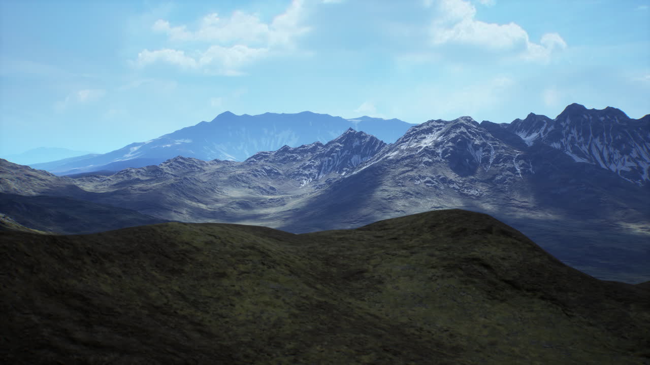 Lush green hills in front of dramatic mountain range under a bright sky