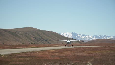 Slowmo---Avión-Despegando-Con-Montañas-Rocosas-Cubiertas-De-Nieve-En-Segundo-Plano.