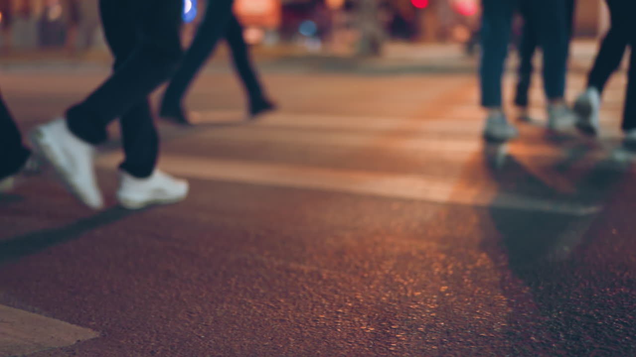 Close view of people walking on a pedestrians across a city street at night with a bokeh background of city lights
