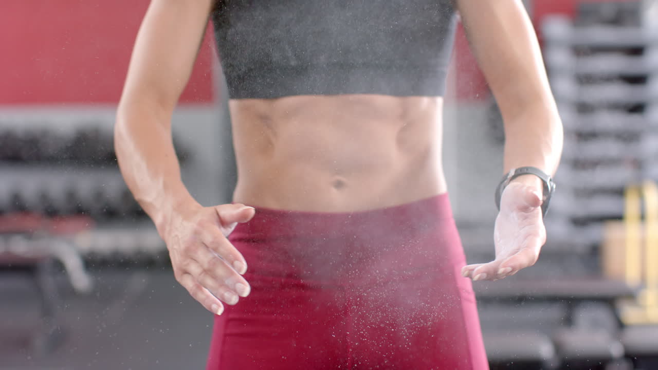 una joven caucásica en forma muestra sus abdominales tonificados en el gimnasio.