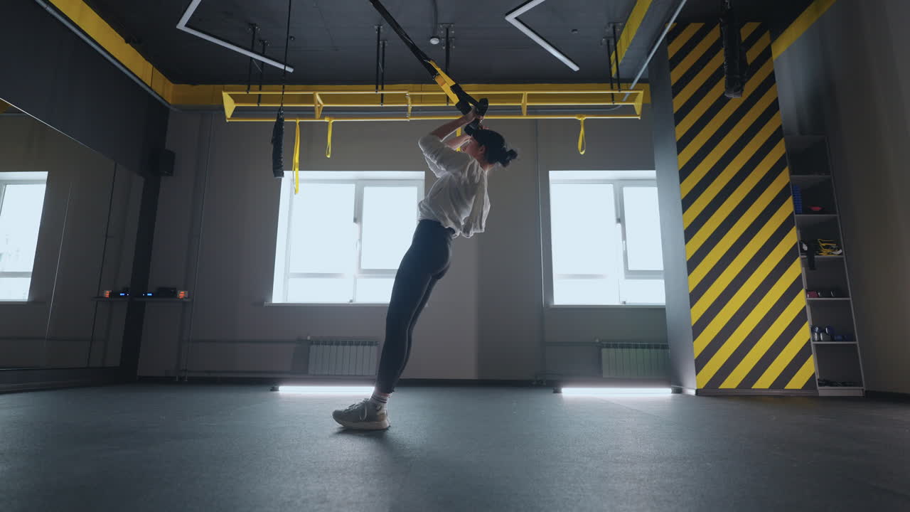 mujer deportiva haciendo ejercicios de trx en el gimnasio. mujeres entrenando con correas de fitness en el gimnasio. mujer hermosa ejercitando sus músculos con correa o correas de suspensión.