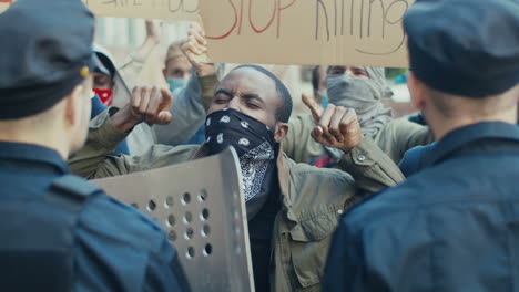 african american man yelling a police officer in a protest with multiethnic group of people in the street