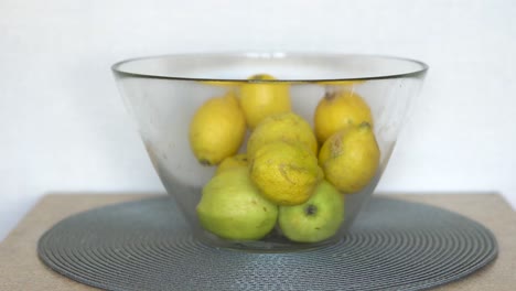 caucasian men picks up a lemon from the fruit bowl in the kitchen