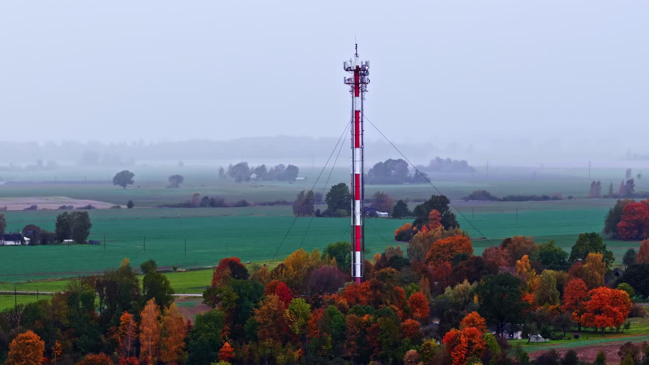 Aerial of tall communication tower surrounded by foggy forest landscape, orbit