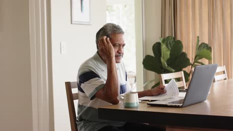 Hombre-Mayor-Birracial-Haciendo-Trámites-Y-Usando-Una-Computadora-Portátil-En-Casa,-Cámara-Lenta