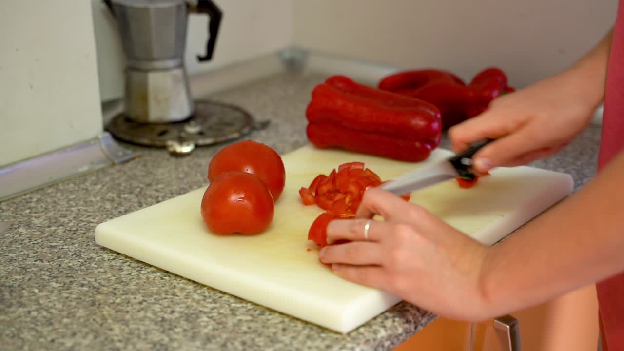 mujer cortando tomates rojos frescos para comer en el tablero de la cocina