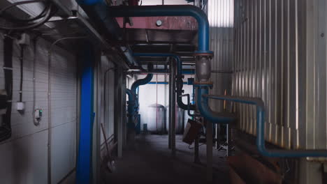 empty aisle with gas pipes and large tanks in boiler house