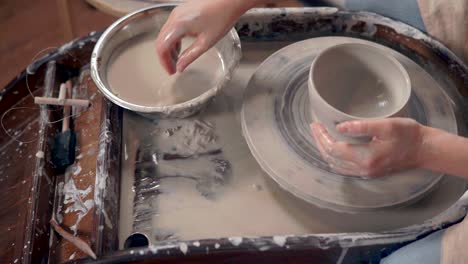 woman shaping clay on pottery wheel