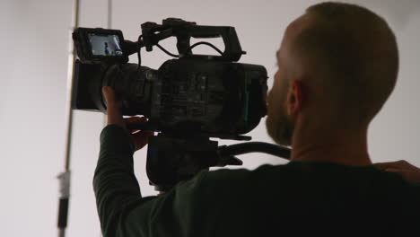 primer plano de un operador de cámara de cine masculino enfocando la cámara usando un monitor filmando o grabando video en el estudio