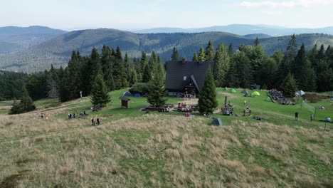 Mountain-shelter-during-a-summer-day-with-mountains-peaks,-forest,-lush-greenery-and-trees