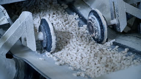 two wheels moving along both sides of conveyor belt. line transporting pressed kaolin clay. close up.