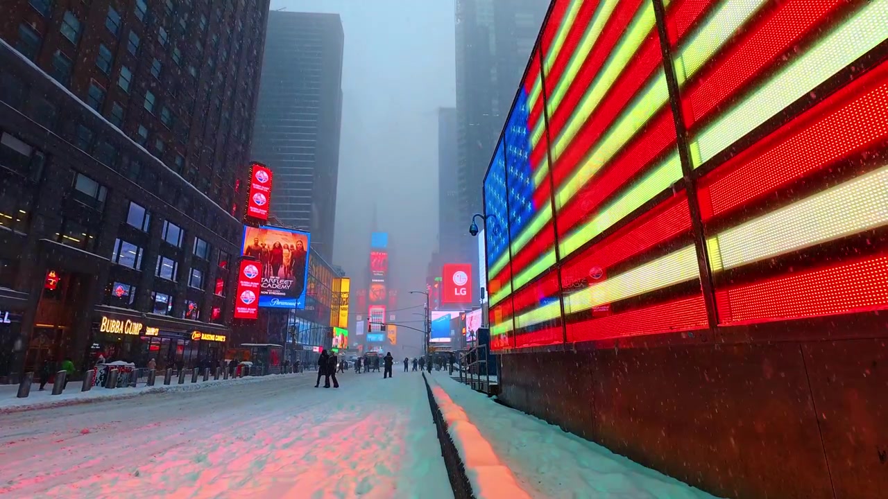 Nova York, EUA, 25 de Dezembro de 2025: Rua Nevada da Times Square ao Lado de um Outdoor com a Bandeira Americana. Times Square com pedestres, neve caindo e uma grande exibição iluminada da bandeira americana.