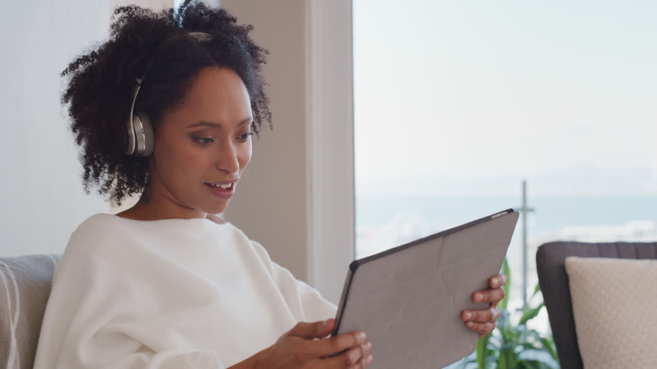 beautiful young woman using tablet computer watching online entertainment at home listening to music enjoying relaxing in luxury penthouse apartment