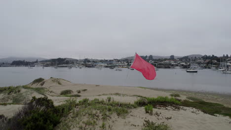 muñeca de círculo aéreo alrededor de la bandera roja ondeando en la playa cerca de la bahía de morro