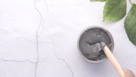 máscara facial de arcilla gris en un frasco con cuchara de madera