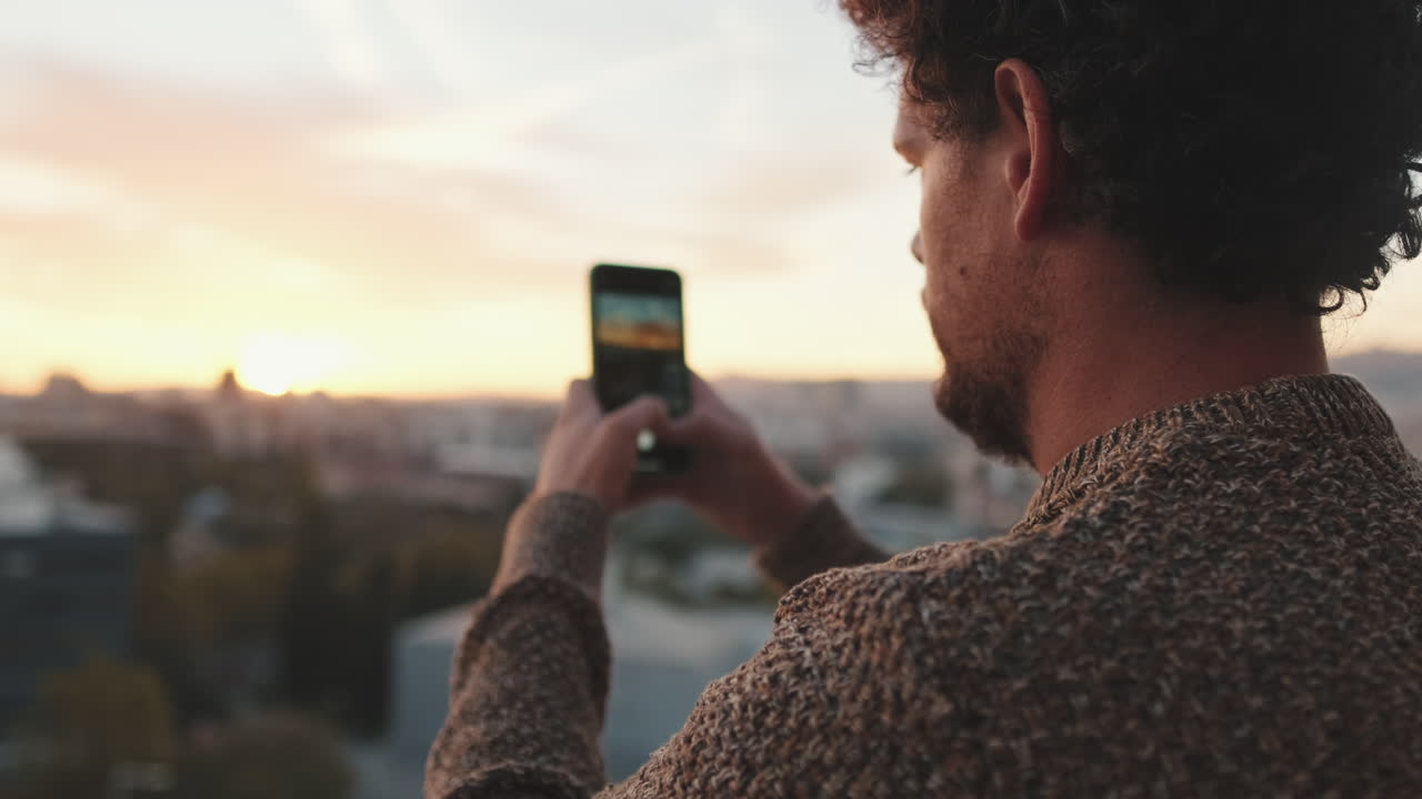 Man taking photo of city at sunset