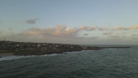 Aerial-drone-flying-over-sea-with-Punta-del-Diablo-village-in-background,-Uruguay