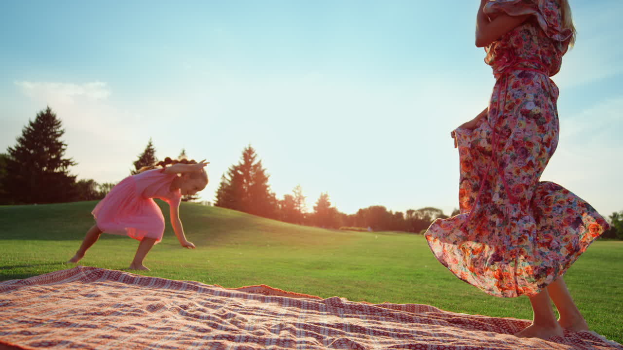 Mother dancing with daughter in city park. Woman and girl having fun outdoor.