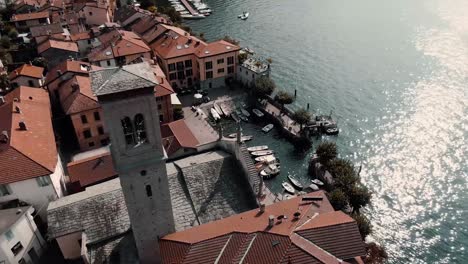 aerial view of the parish of saint tecla at the shore of lake como in torno, como, italy - orbiting drone shot