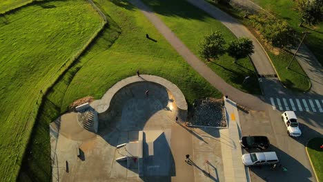 Zeitlupenaufnahme-Einer-Luftdrohne-Von-Oben,-Die-Die-Aktionen-Von-Skateboardern-Erfasst,-Die-Bei-Sonnenuntergang-Im-Heritage-Skate-Park-üben