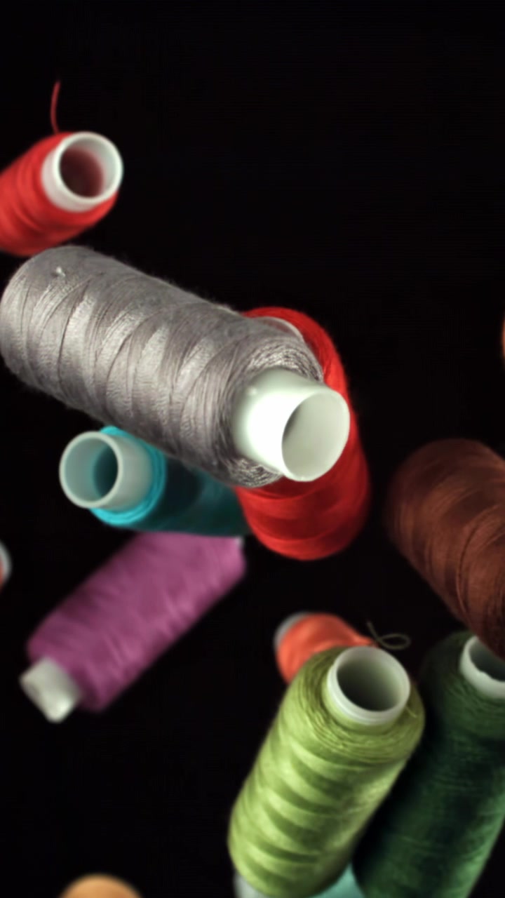 Colorful Spools of Sewing Thread Floating on Black Background