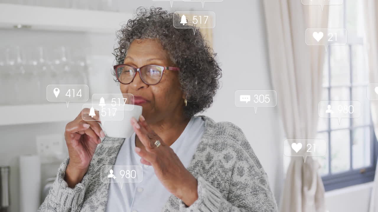 Senior woman sipping coffee in bright kitchen, with floating digital marketing notification icons