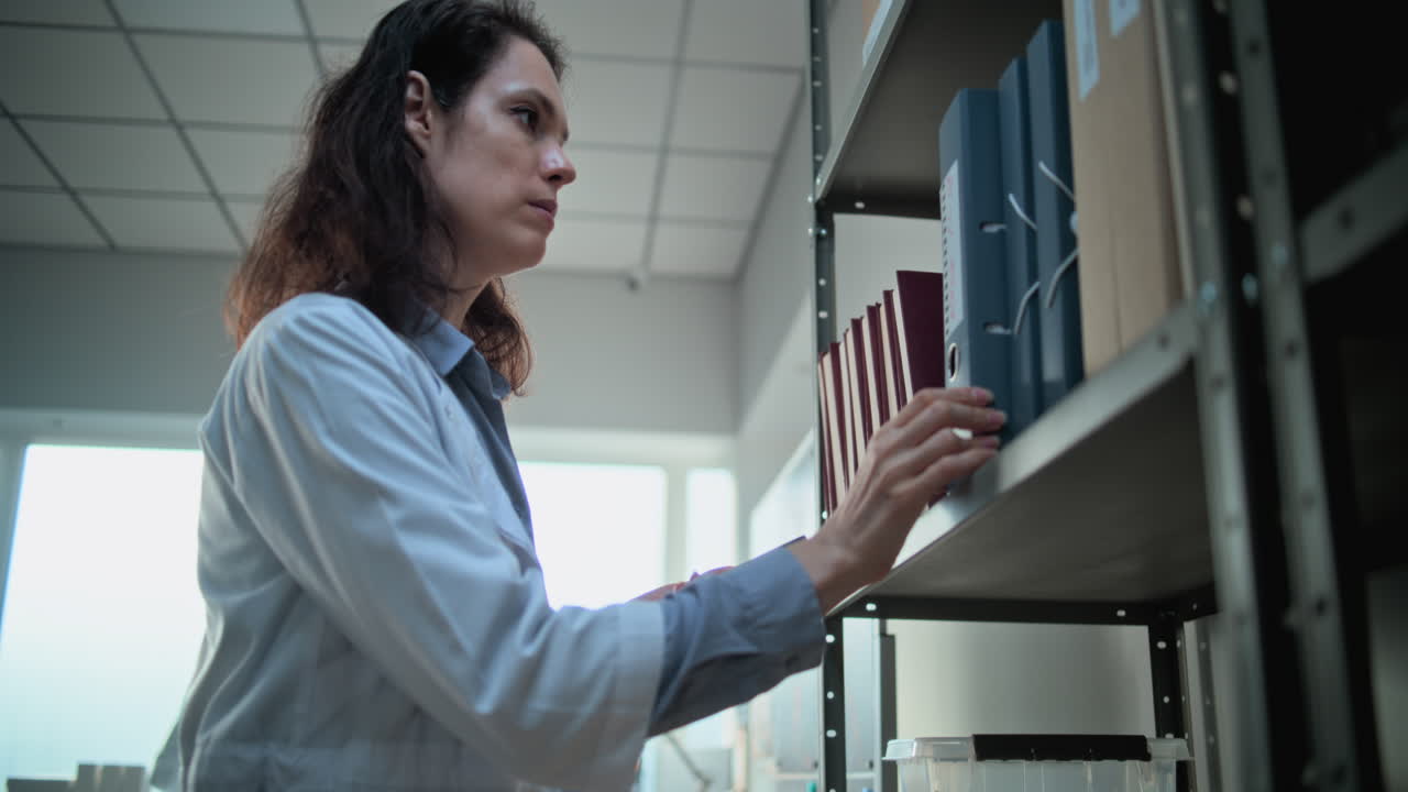 mujer en bata de laboratorio usando teléfono inteligente en la oficina