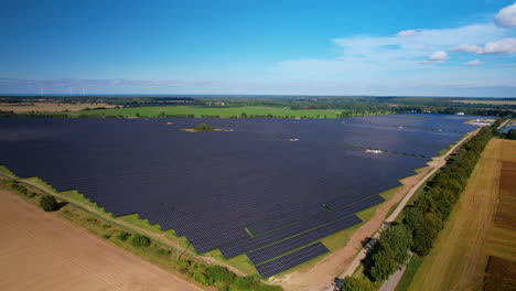 solar photovoltaic farm, drone aerial flying over massive solar panel array field in poland on a sunny day