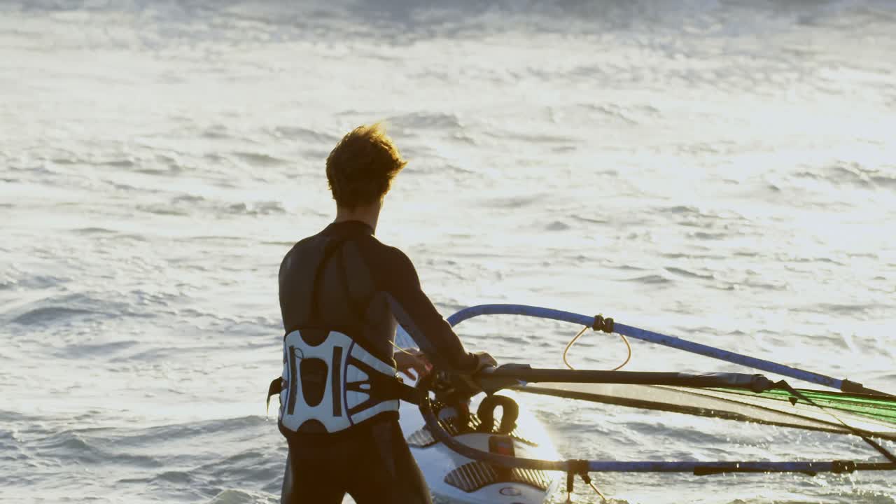surfista masculino haciendo windsurf en la playa 4k
