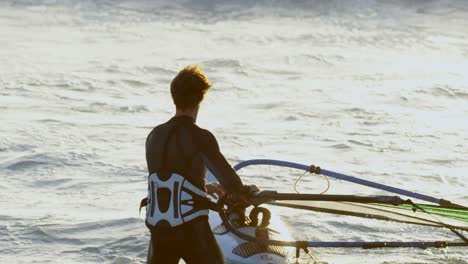 surfista masculino haciendo windsurf en la playa 4k