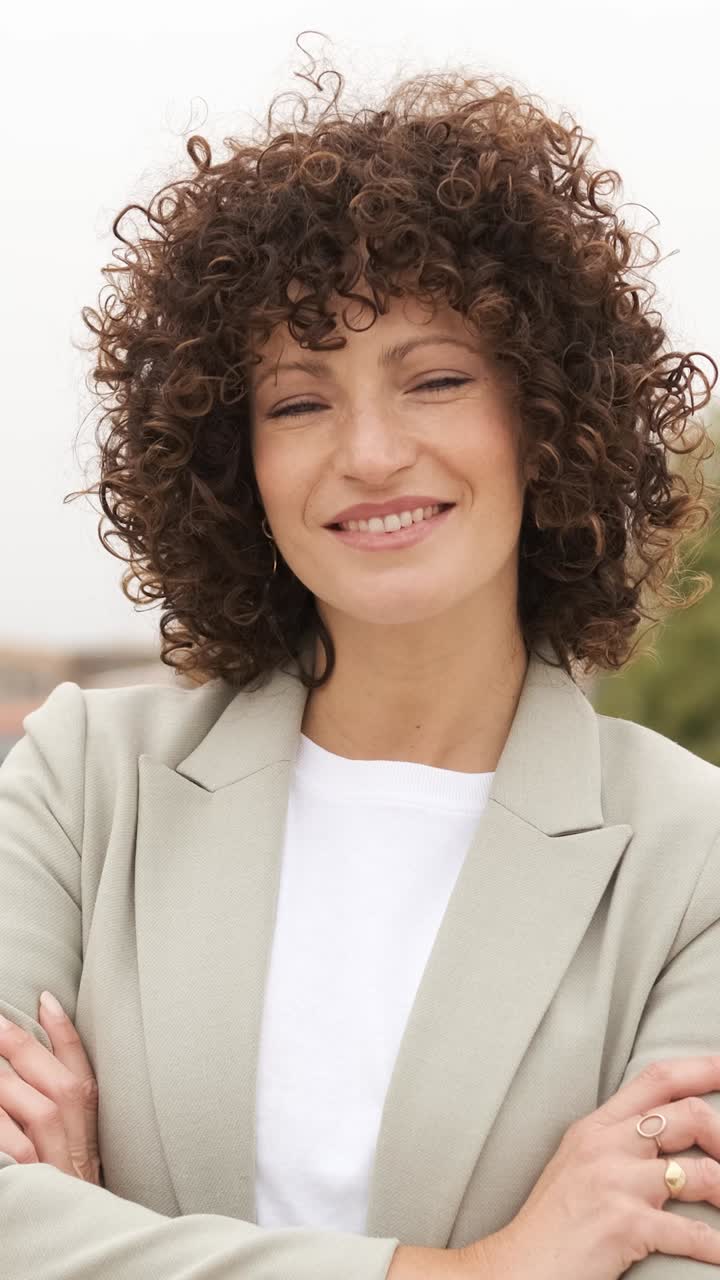 Confident businesswoman smiling with arms crossed in a professional setting. Vertical