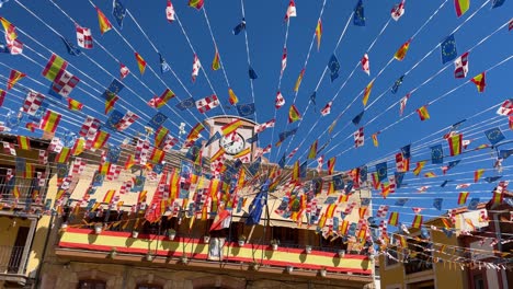 excellent filming of a town square during festivals where a beautiful decoration of united flags appears from the town hall, which is the building that has the clock, it is in slow motion