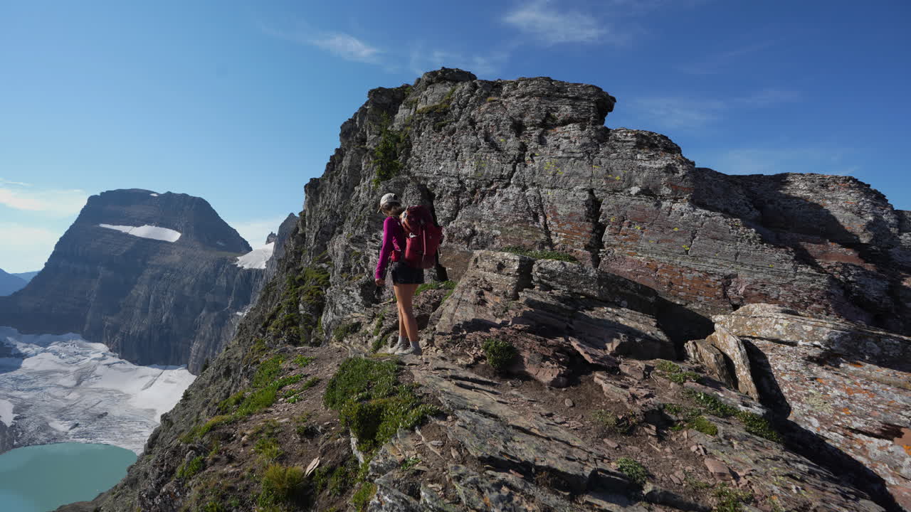 vista trasera de una excursionista con mochila en el punto de vista sobre el lago grinnell en el parque nacional glacier, montana, estados unidos