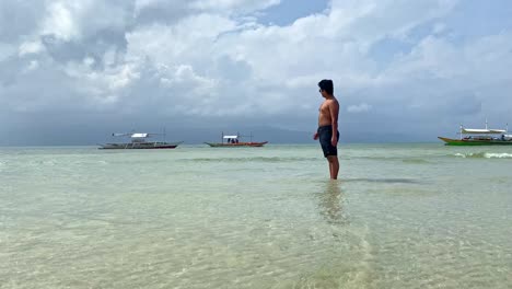 young tourist admiring tropical beach filled with bangka boats - philippines travel and destinations